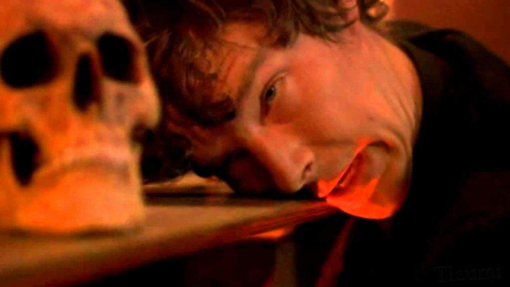 Sherlock leaning with his head next to a
skull