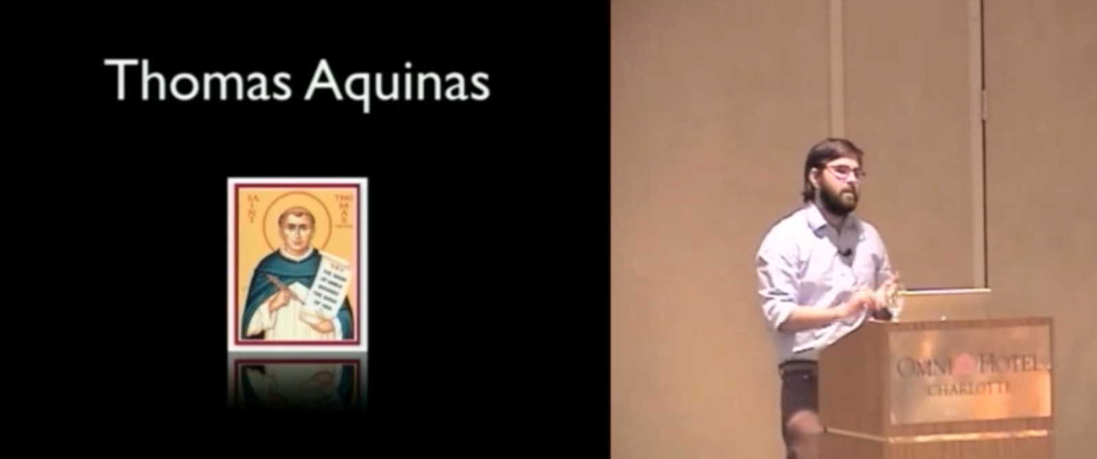 Painting of Thomas Aquinas on a conference slide, alongside speaker Marcel Molina