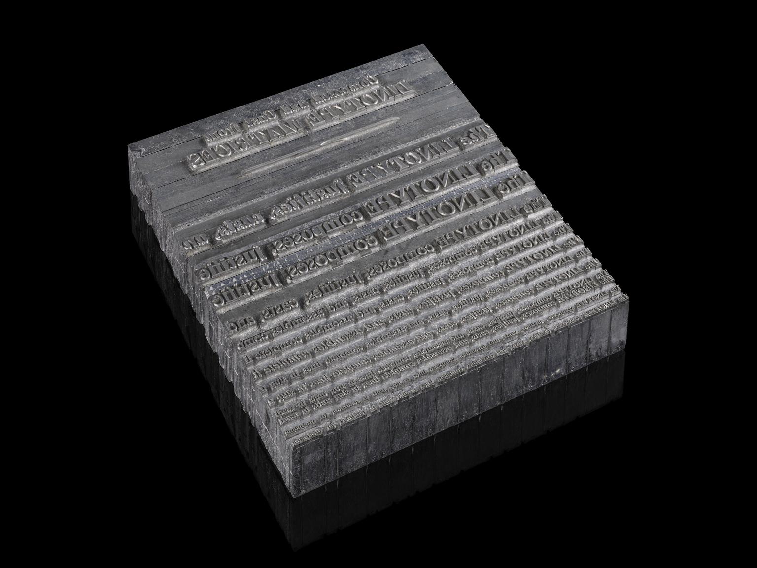 A gray slab of metal with various lines of serif type set as part of that metal. The slab is against a black background.