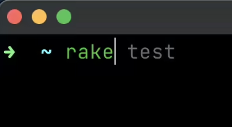 A shell prompt with the 'rake' command typed. After it, there is a suggestion 'test' in light gray